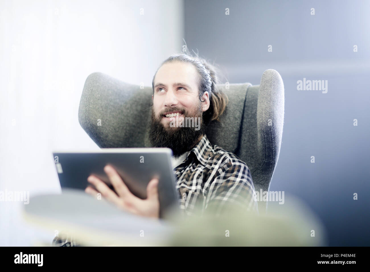 Couple assis dans un fauteuil à l'aide d'une tablette numérique Banque D'Images