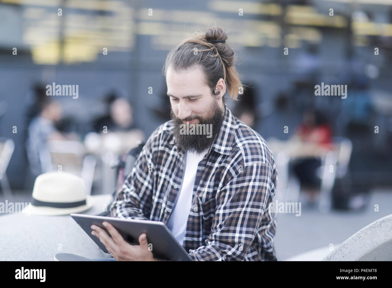 Smiling Man sitting outdoors using a digital tablet Banque D'Images