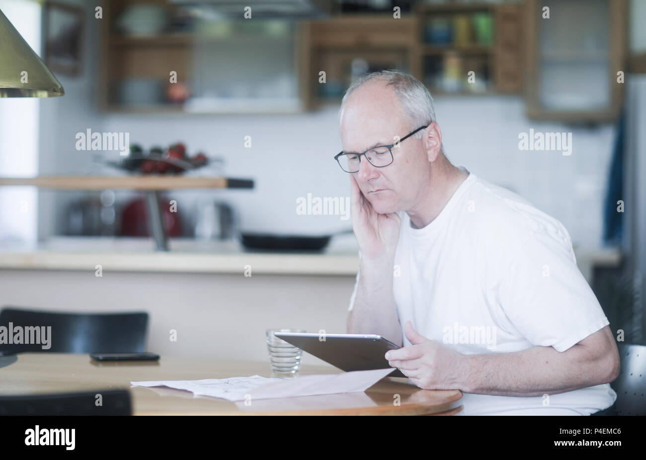 L'homme assis à une table à l'aide d'une tablette numérique Banque D'Images