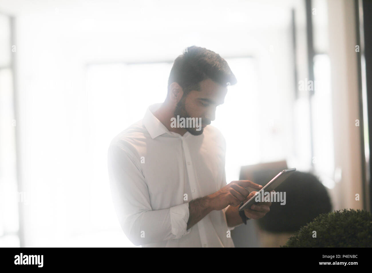 Homme debout à l'intérieur à l'aide d'une tablette numérique Banque D'Images