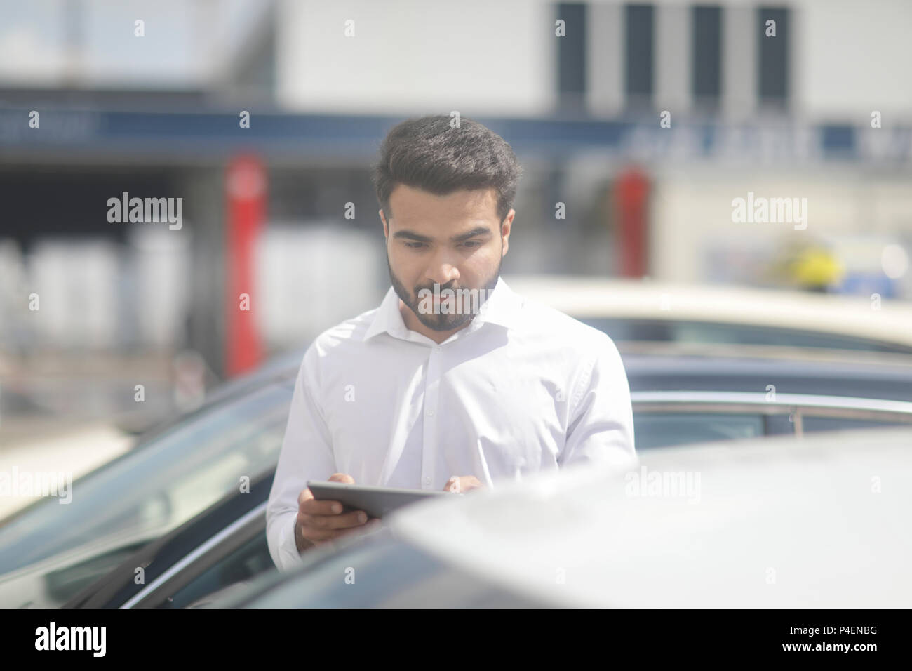 Homme debout par une voiture à l'aide d'une tablette numérique Banque D'Images