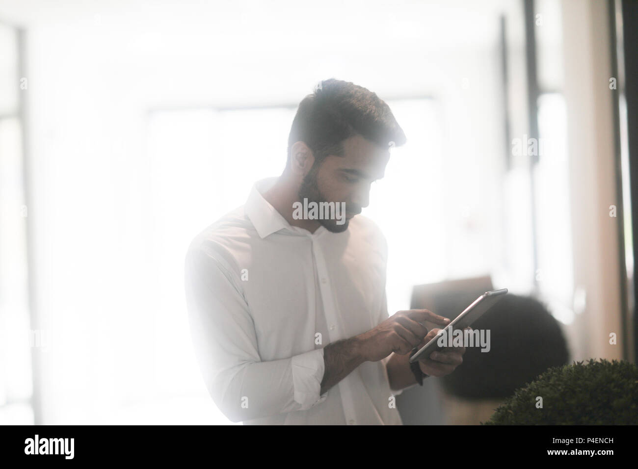 Homme debout dans un bureau à l'aide d'une tablette numérique Banque D'Images