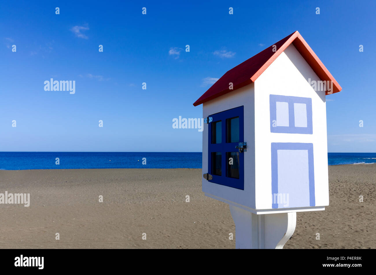 Un modèle miniature d'une maison avec une plage volcanique foncé et un ciel bleu en arrière-plan Banque D'Images