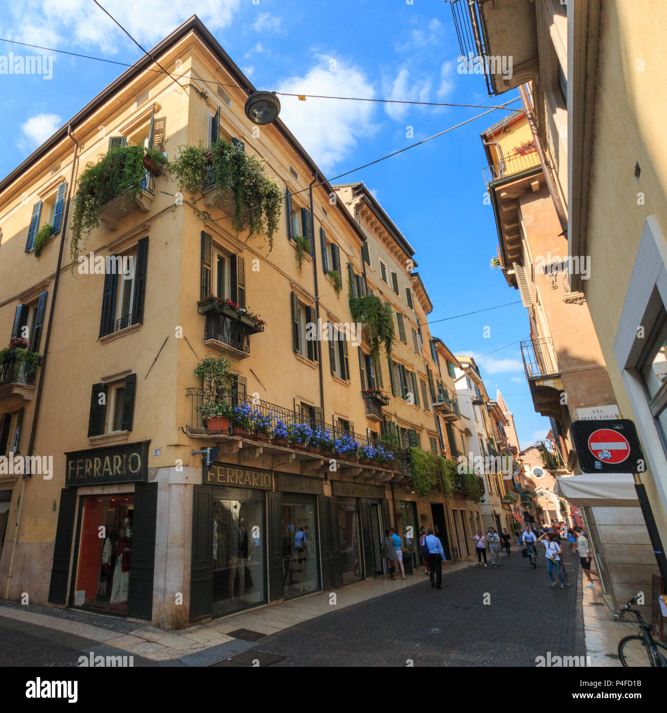 Vérone, Italie - 26 mai 2017 : Chambre avec des magasins et des fleurs bleues sur un balcon dans une zone piétonne à Vérone, Italie Banque D'Images