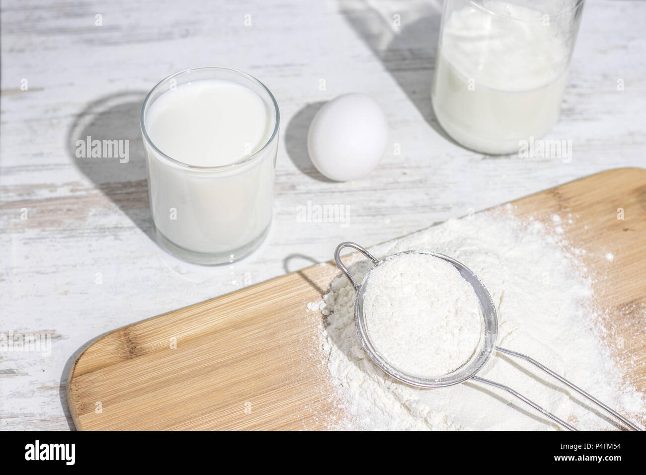 Ingrédients blanc à la cuisine : le lait dans le verre, l'oeuf et de la farine avec de longues ombres Banque D'Images