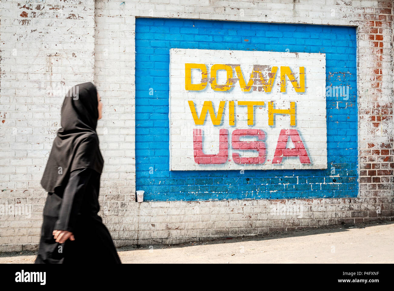 Femme musulmane voilée marcher par la propagande anti-américaine et Israël murale sur Téhéran iran en dehors de la rue ancienne ambassade des Etats-Unis Banque D'Images
