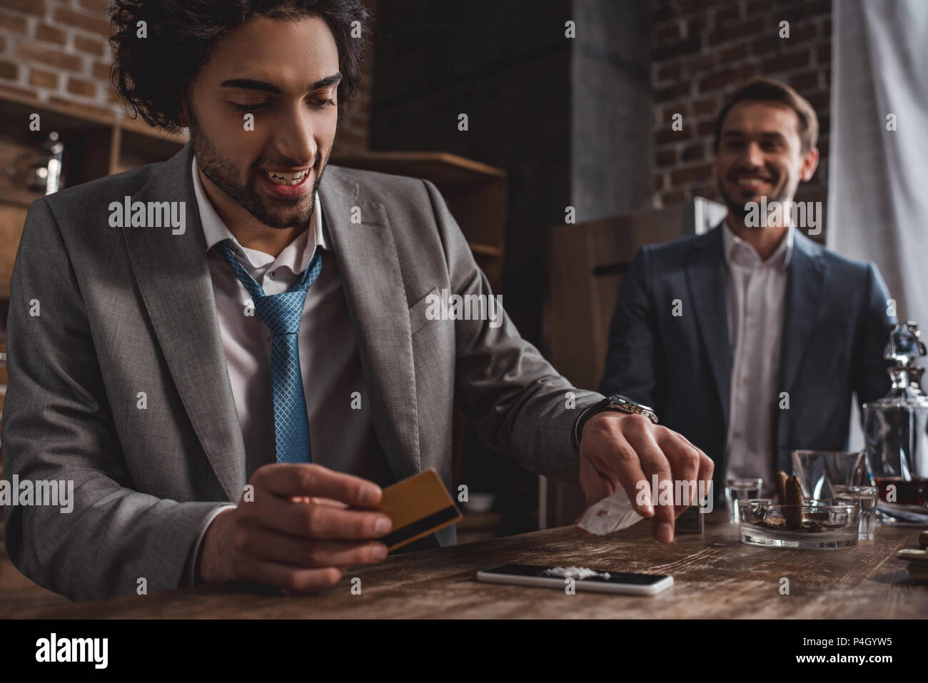 Close-up view of smiling man in suit prendre des drogues tout en ami debout derrière Banque D'Images