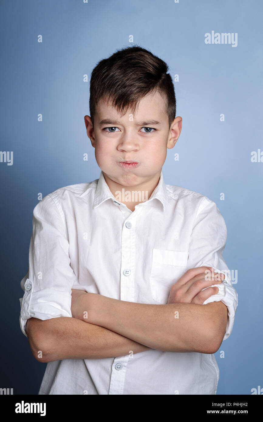 Closeup portrait de jeune garçon en colère, dépression nerveuse, isolé sur fond bleu. Des émotions négatives, les expressions du visage, les sentiments de réaction à Banque D'Images