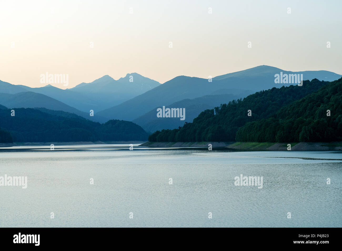 Lac calme au coucher du soleil. Lac Vidraru est un lac artificiel dans les montagnes de Fagaras, comté d'Arges, Roumanie Banque D'Images