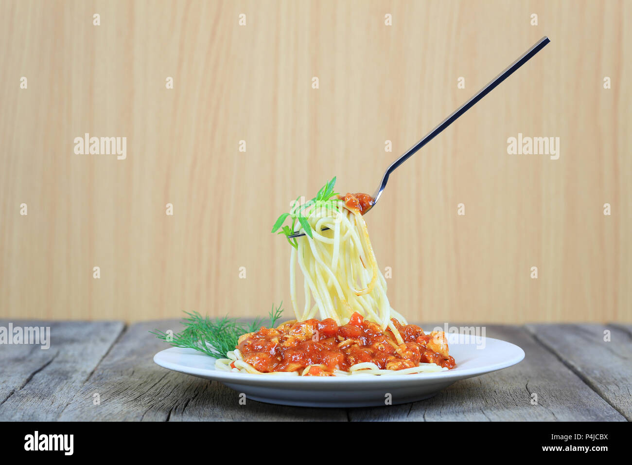 Spaghetti à la sauce tomate sur la fourche d'argent flottant dans le plat blanc sur plancher en bois,concept de manger de la bonne nourriture est les soins de santé. Banque D'Images