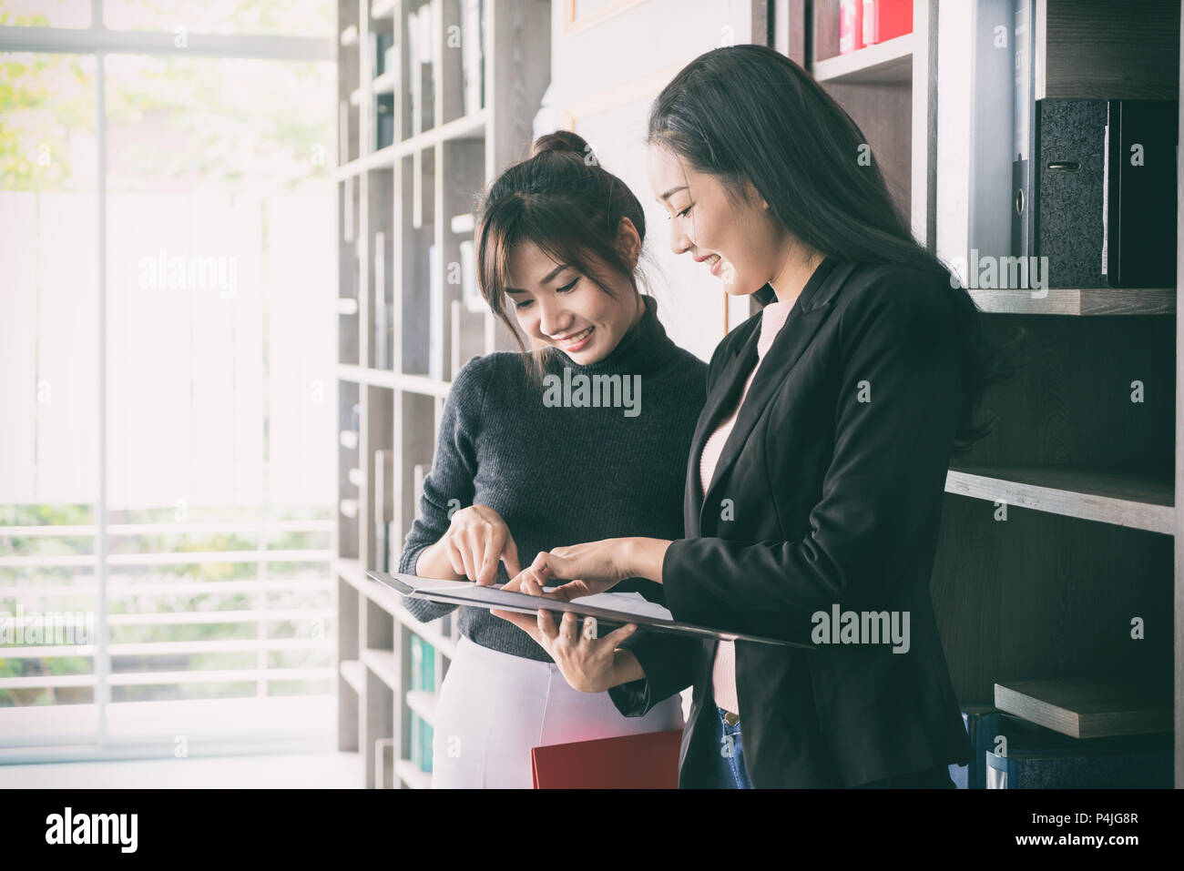 Asian businesswoman deux collègues l'un à côté de l'autre dans un bureau. Ils businesswoman parle de rapport dans des fichiers. Banque D'Images