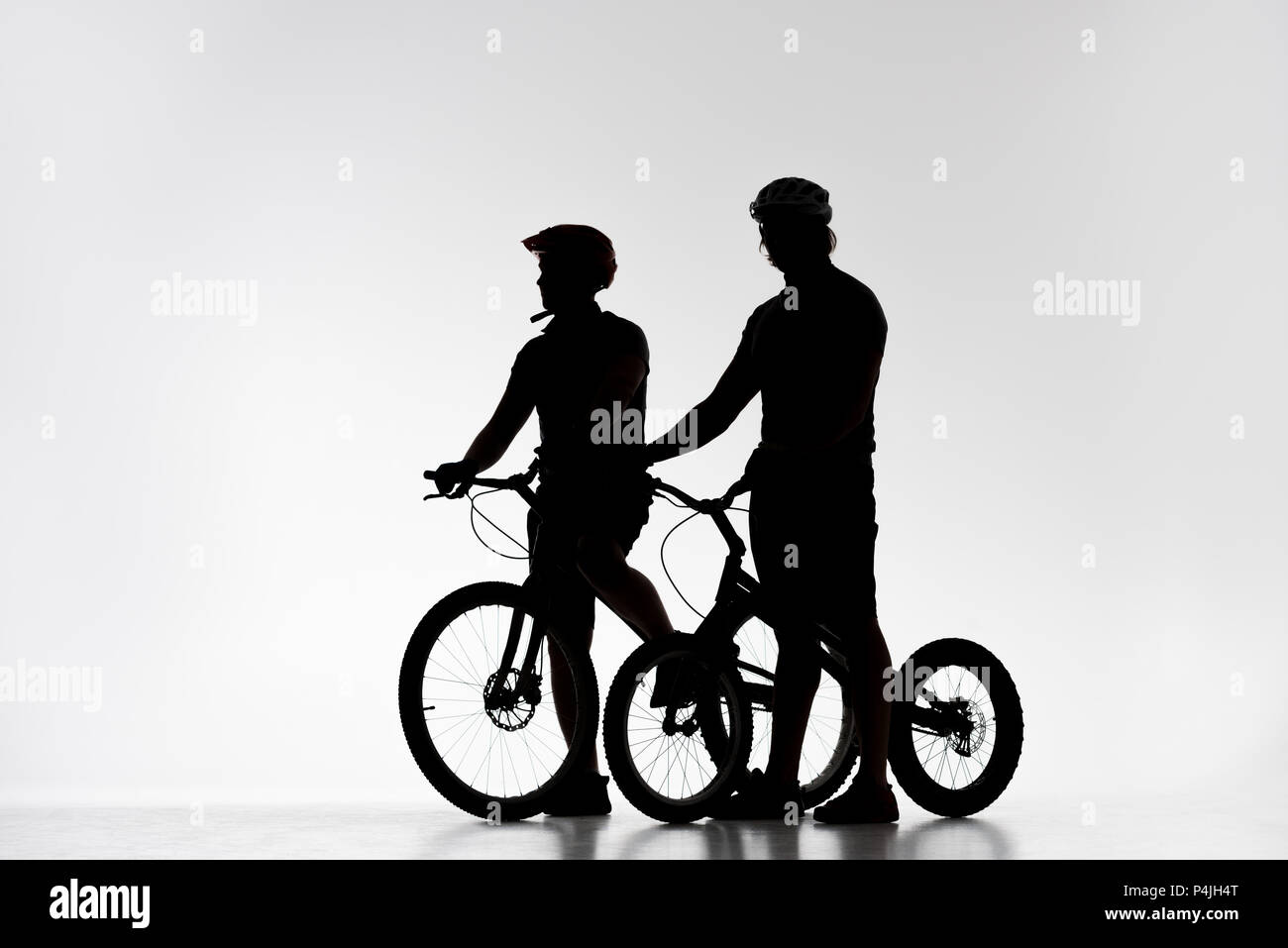 Silhouettes de motards en procès avec les casques de bicyclettes sur white Banque D'Images