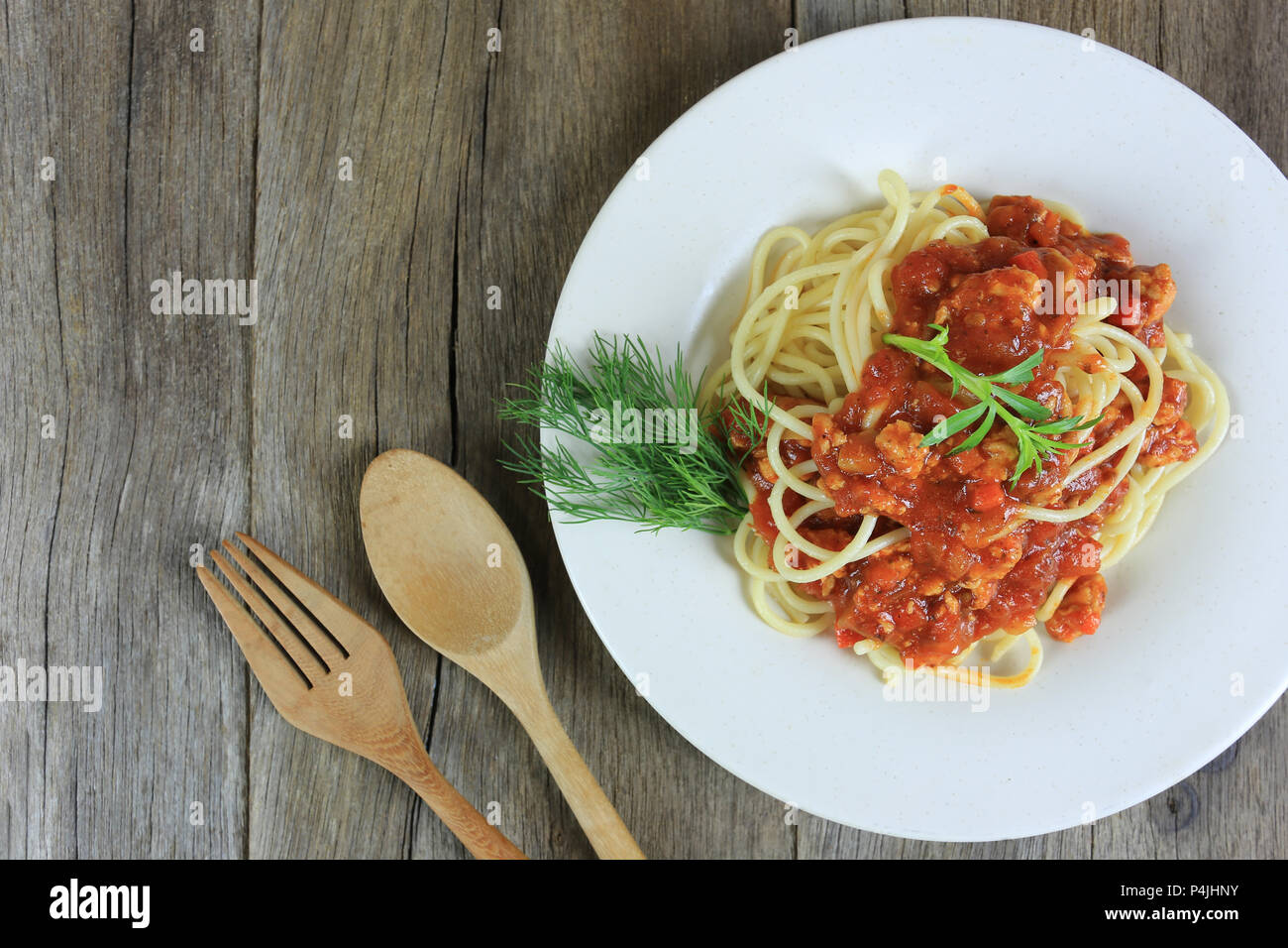 Spaghetti à la sauce tomate dans un plat blanc sur un sol en parquet et d'arrière-plan ont copie espace dans la notion de manger de la bonne nourriture est les soins de santé. Banque D'Images