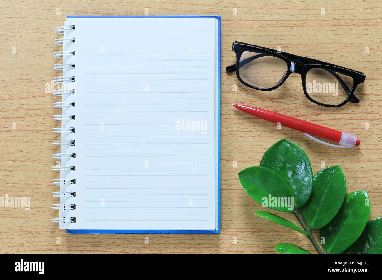 Note de papier vierge et de lunettes placé sur un plancher en bois marron pour la conception dans votre travail concept. Banque D'Images