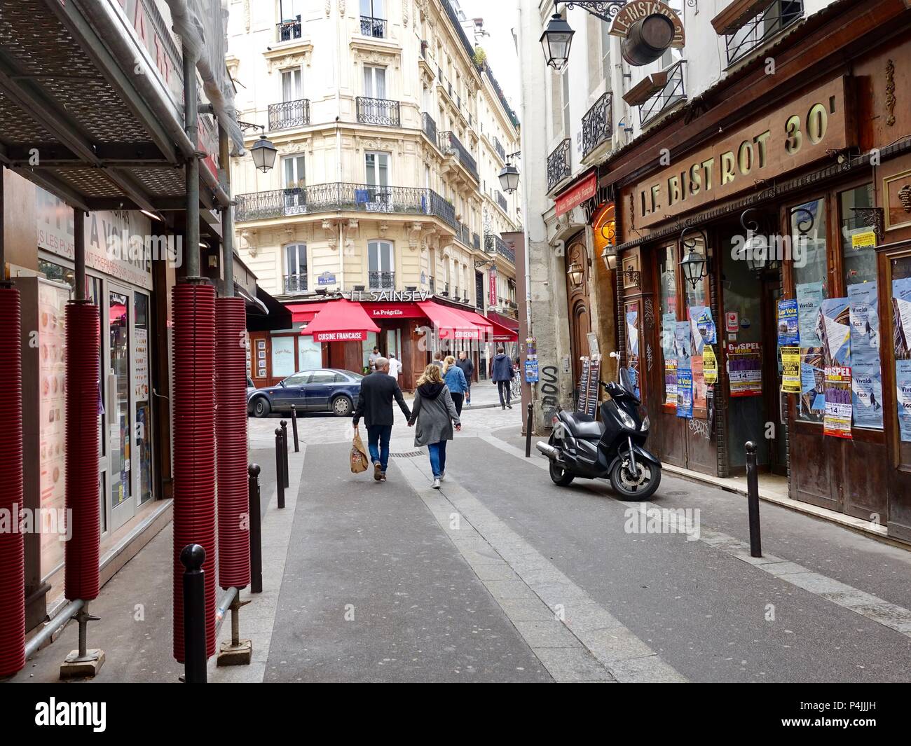 Couple walking down rue étroite de la rue Saint Severin vers la rue de la Harpe dans le Quartier Latin, Pais, France. Banque D'Images