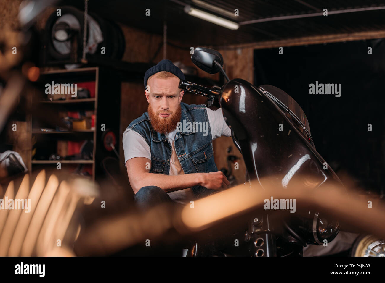 Portrait de beau jeune homme sur le vélo au garage Banque D'Images