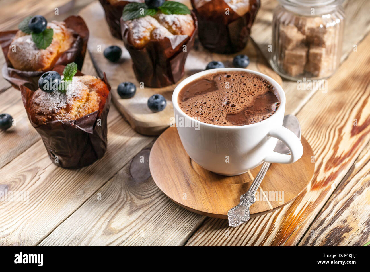 Muffins aux myrtilles et une tasse de chocolat chaud sur un fond de bois à pâte fait maison. Banque D'Images
