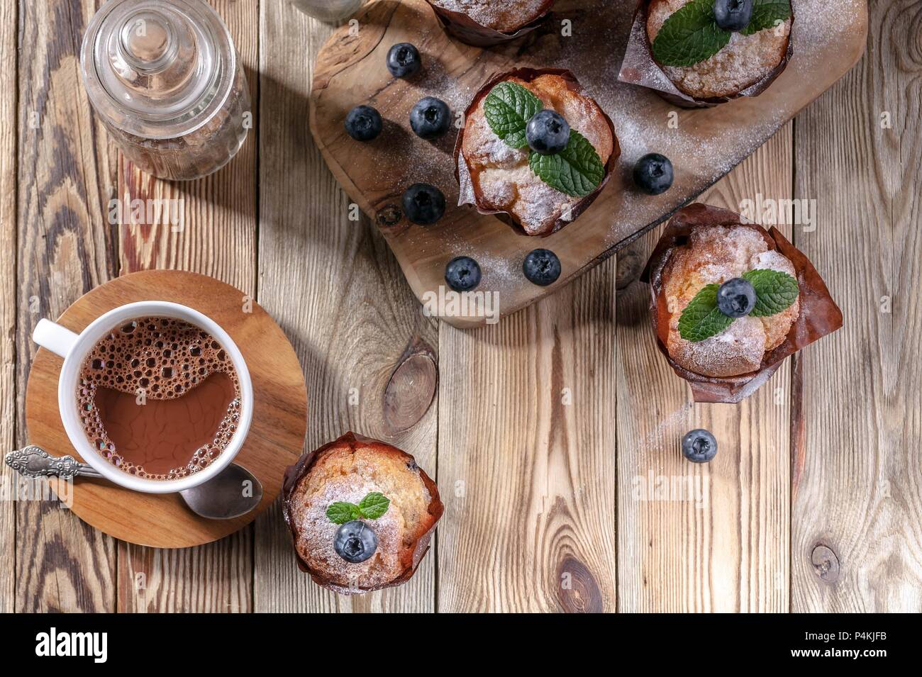 Muffins aux myrtilles et une tasse de chocolat chaud sur un fond de bois à pâte fait maison.. Vue d'en haut Banque D'Images