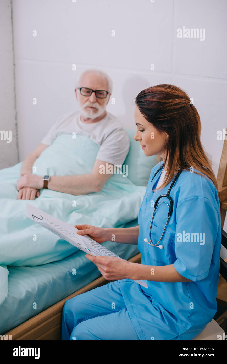 Infirmière expliquant des conseils médicaux aux vieux au lit du patient Banque D'Images