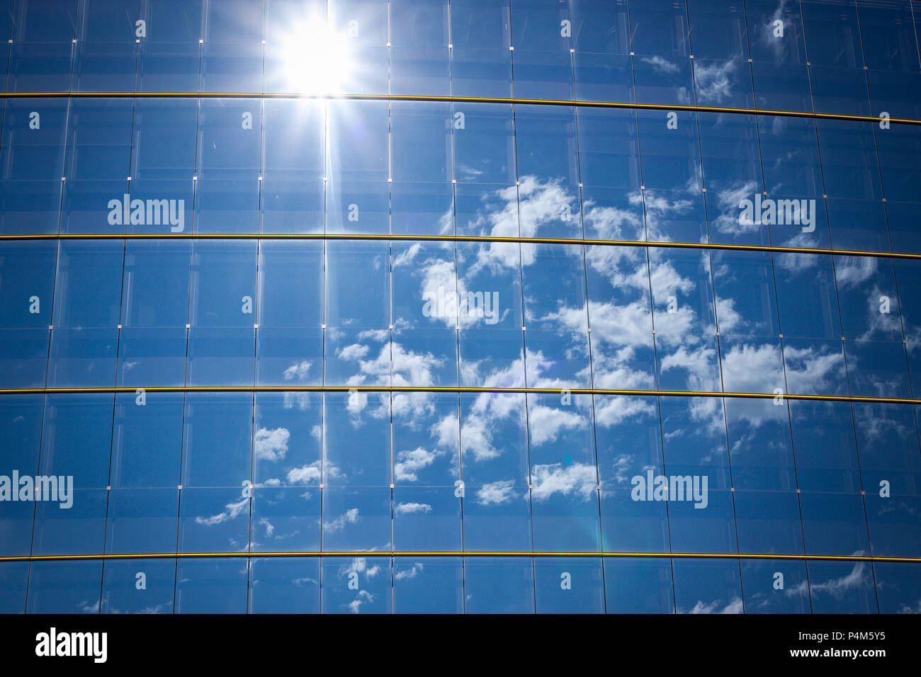 Immeuble de bureaux moderne en verre avec motif avec soleil et nuages reflétée Banque D'Images