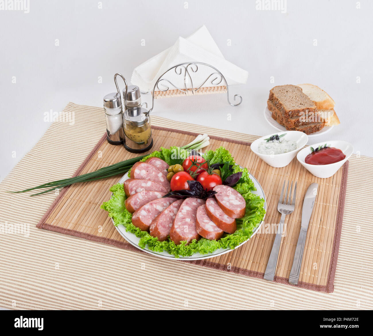 Saucisse fumée avec tomates et feuilles de laitue sur une assiette. Peut être utilisé dans la publicité et dans le développement de sites. Banque D'Images