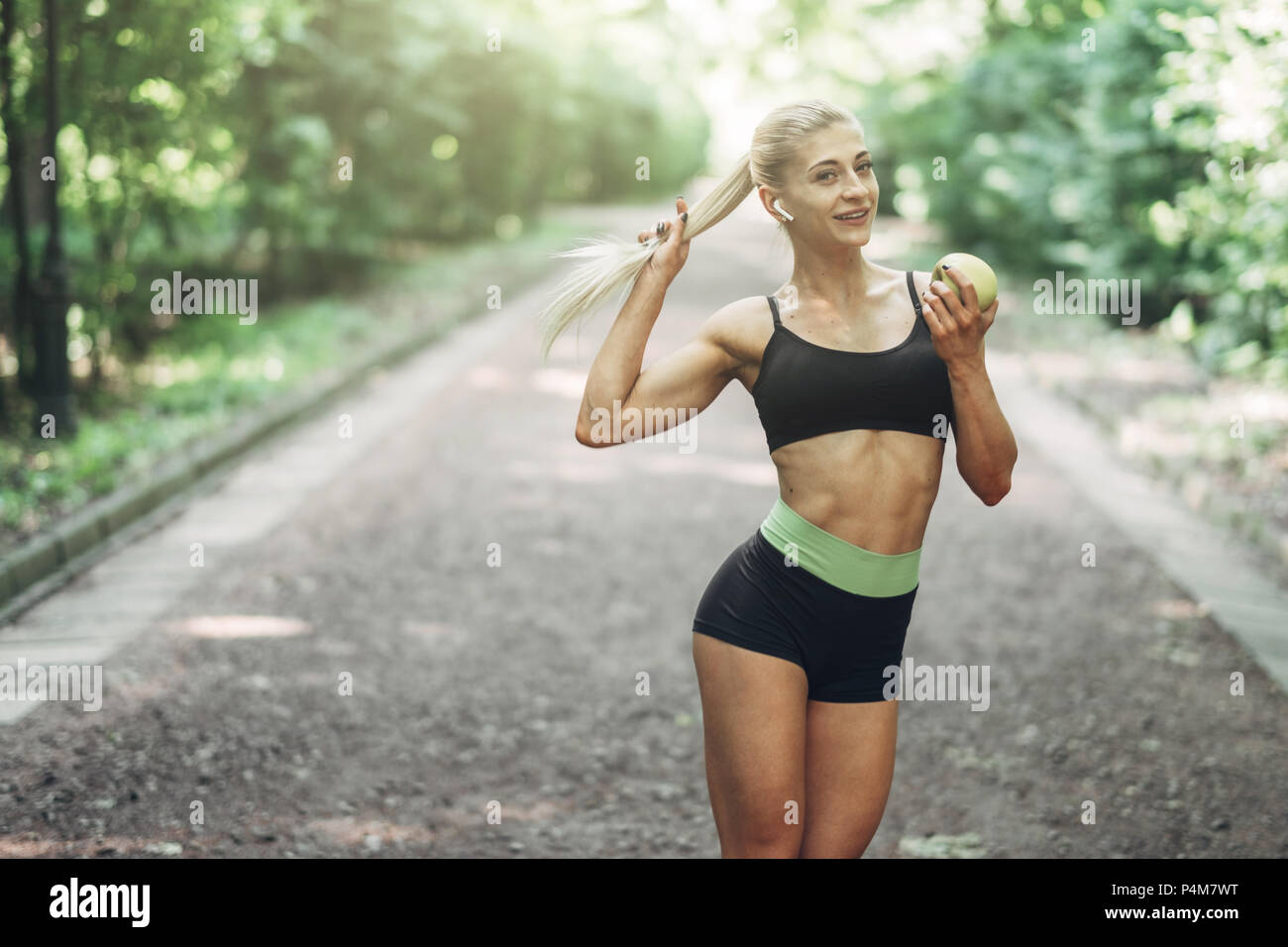 Young Woman in a black Sportswear détient Green Apple en l'Openair. Concept de mode de vie sain. Banque D'Images