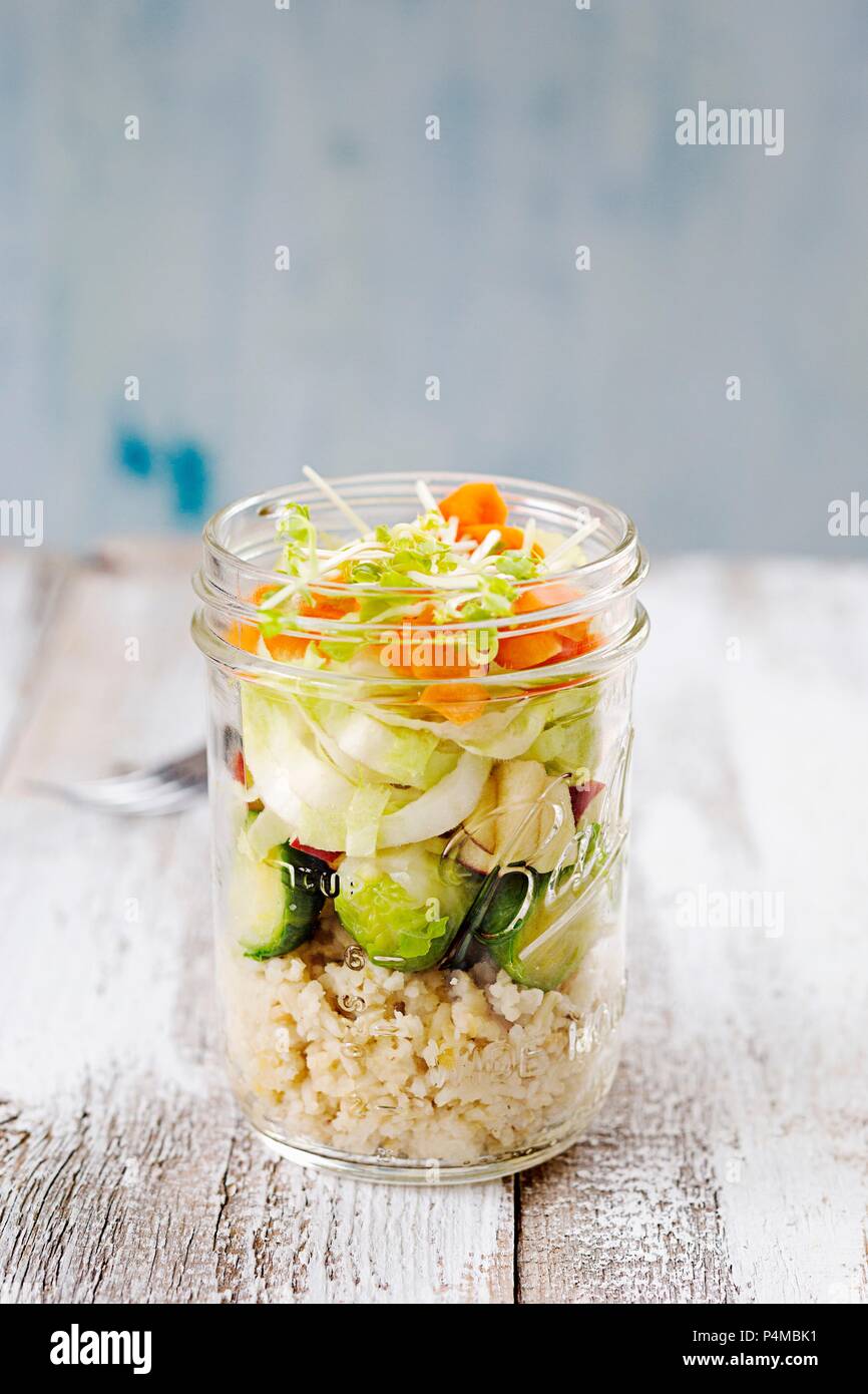 Salade dans un verre avec du couscous, choux de Bruxelles, pommes, endives, carottes et germes de lentilles Banque D'Images