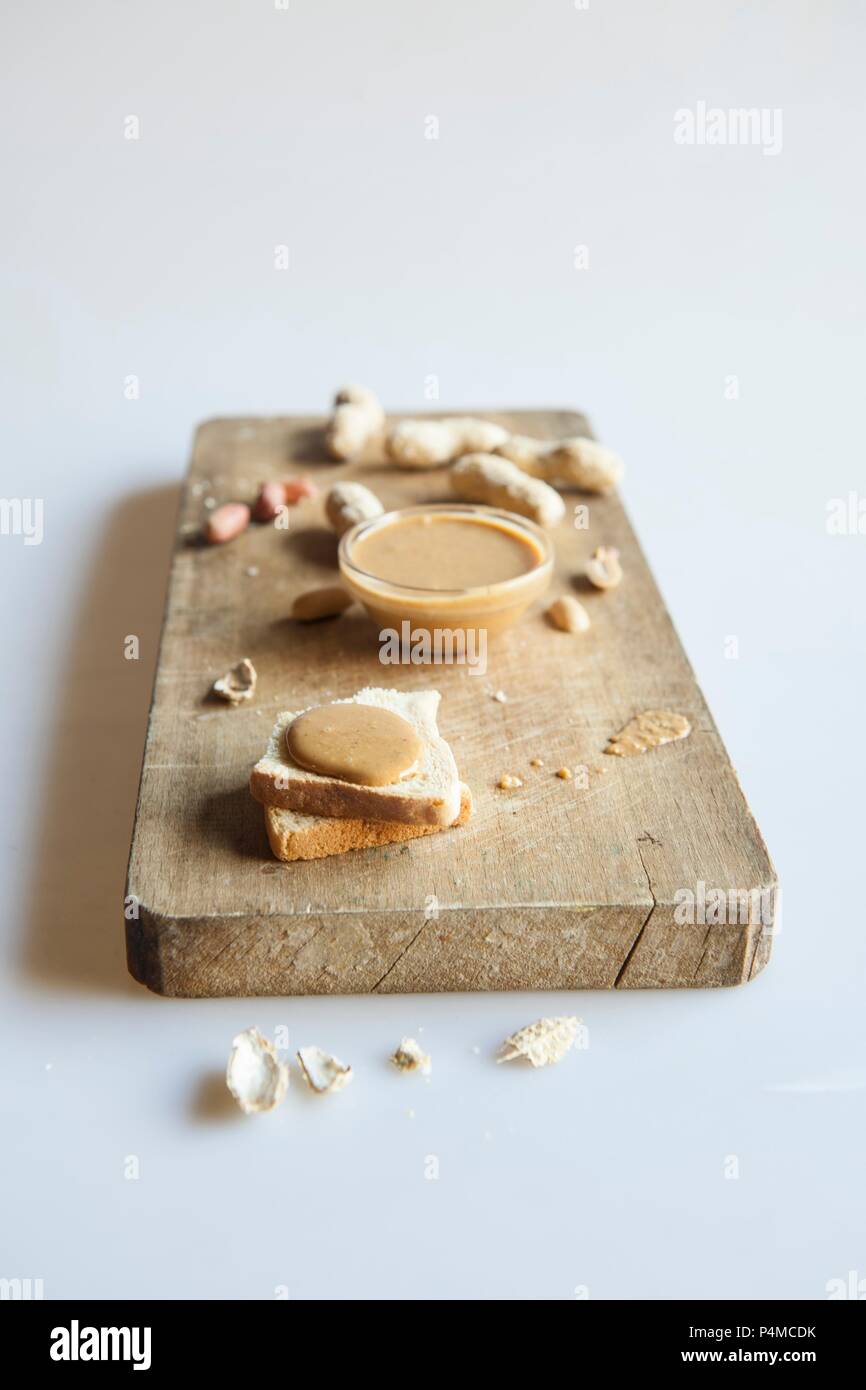 Toast garni de beurre d'arachide, arachides on a chopping board Banque D'Images