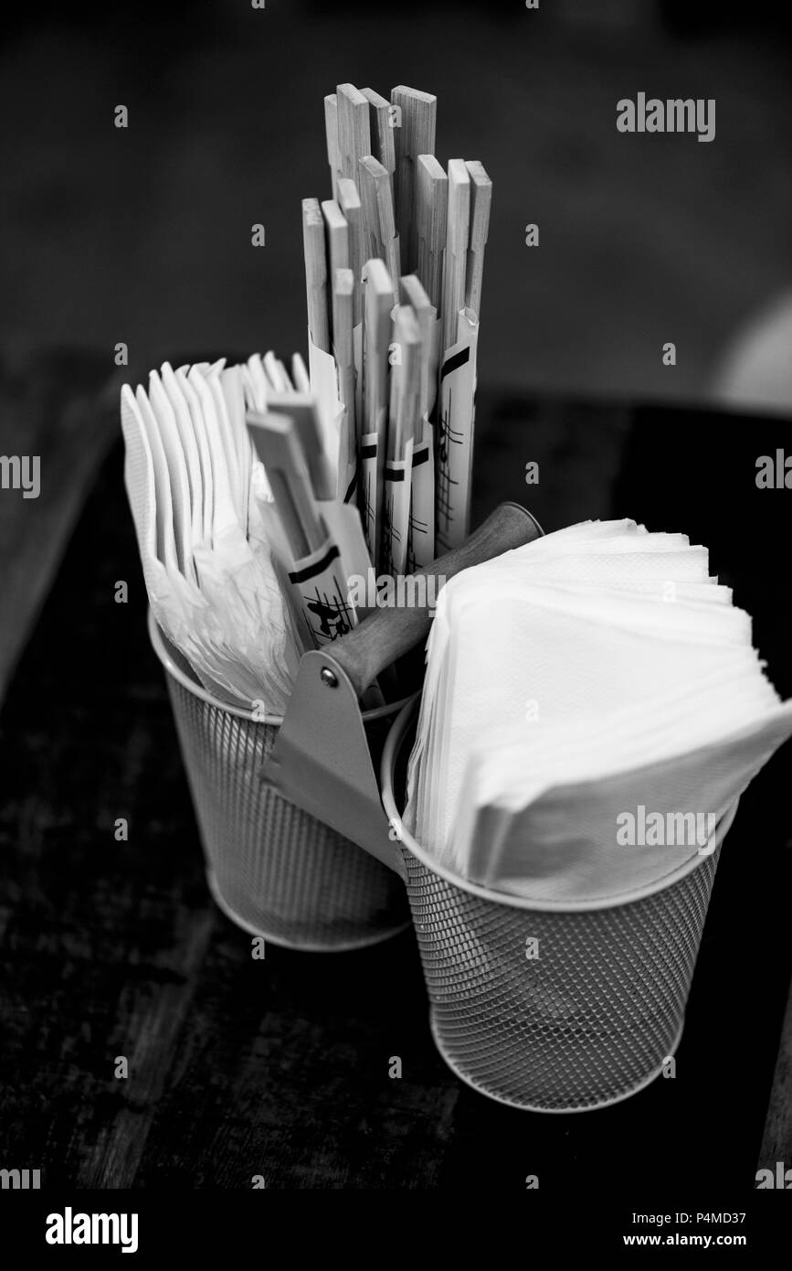 Baguettes et des serviettes en papier dans des conteneurs métalliques sur une table de restaurant Banque D'Images