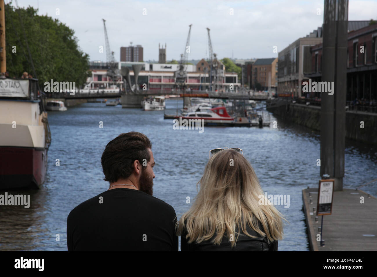 Un jeune couple assis sur une large Quay, Bristol, Angleterre. Banque D'Images