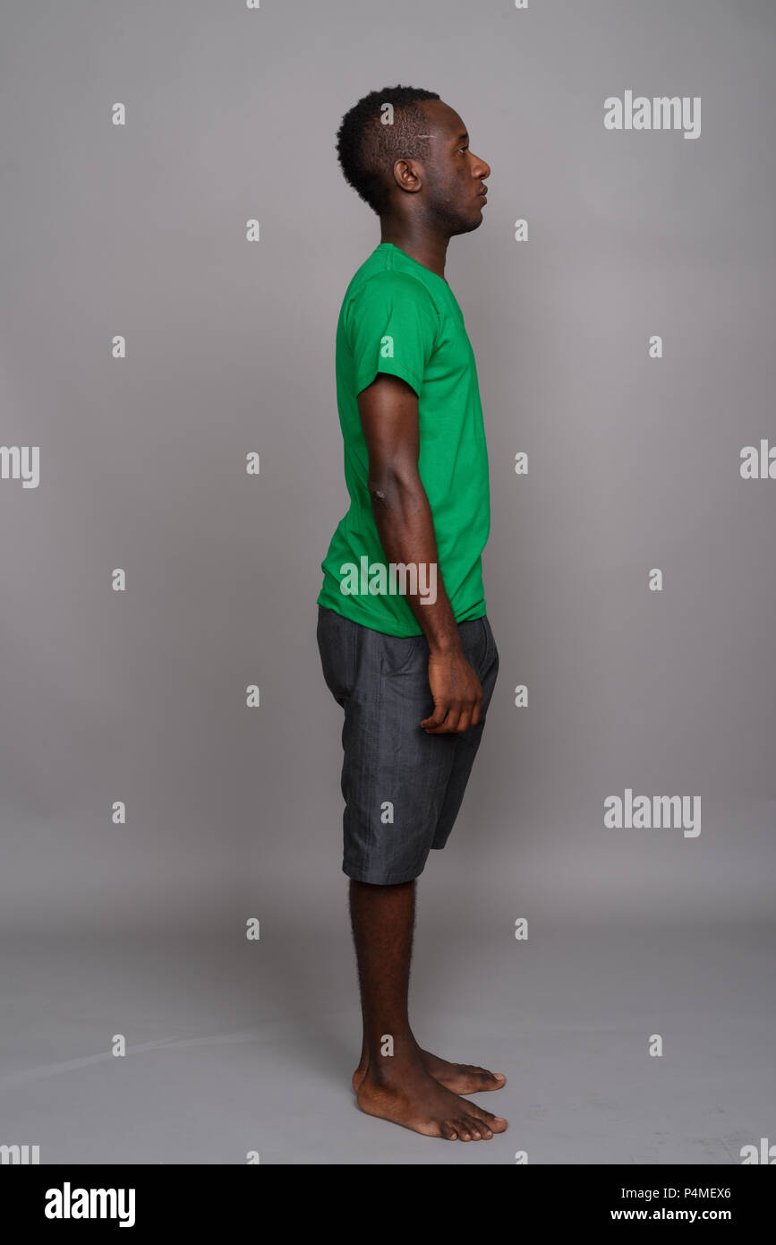 Young African man wearing green shirt contre l'arrière-plan gris Banque D'Images