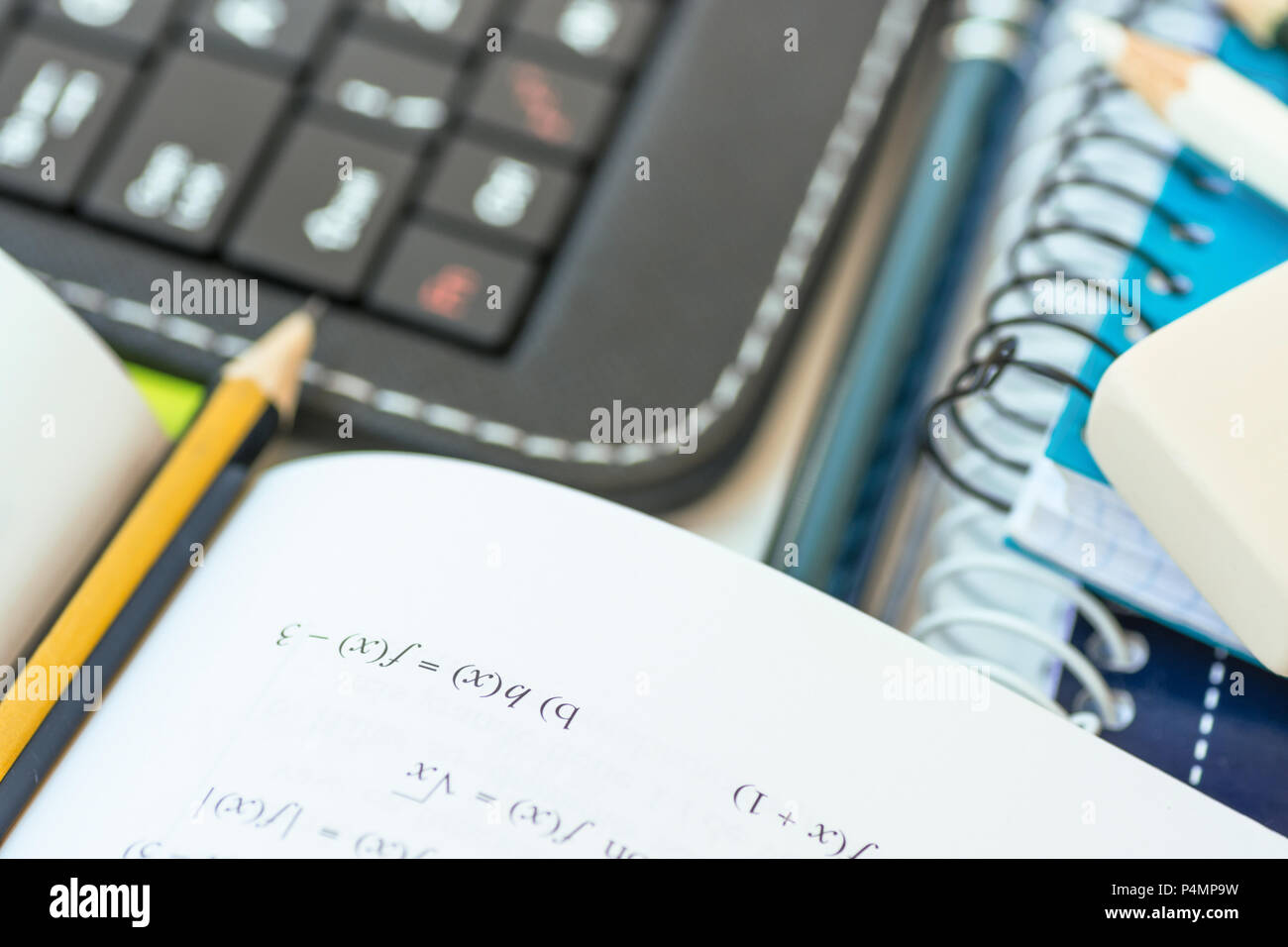 Concept Retour à l'école. Composition de l'ordinateur portable Clavier Tablette Fournitures Stylo caoutchouc cahier ouvert avec formule mathématiques marqué au crayon sur Whi Banque D'Images