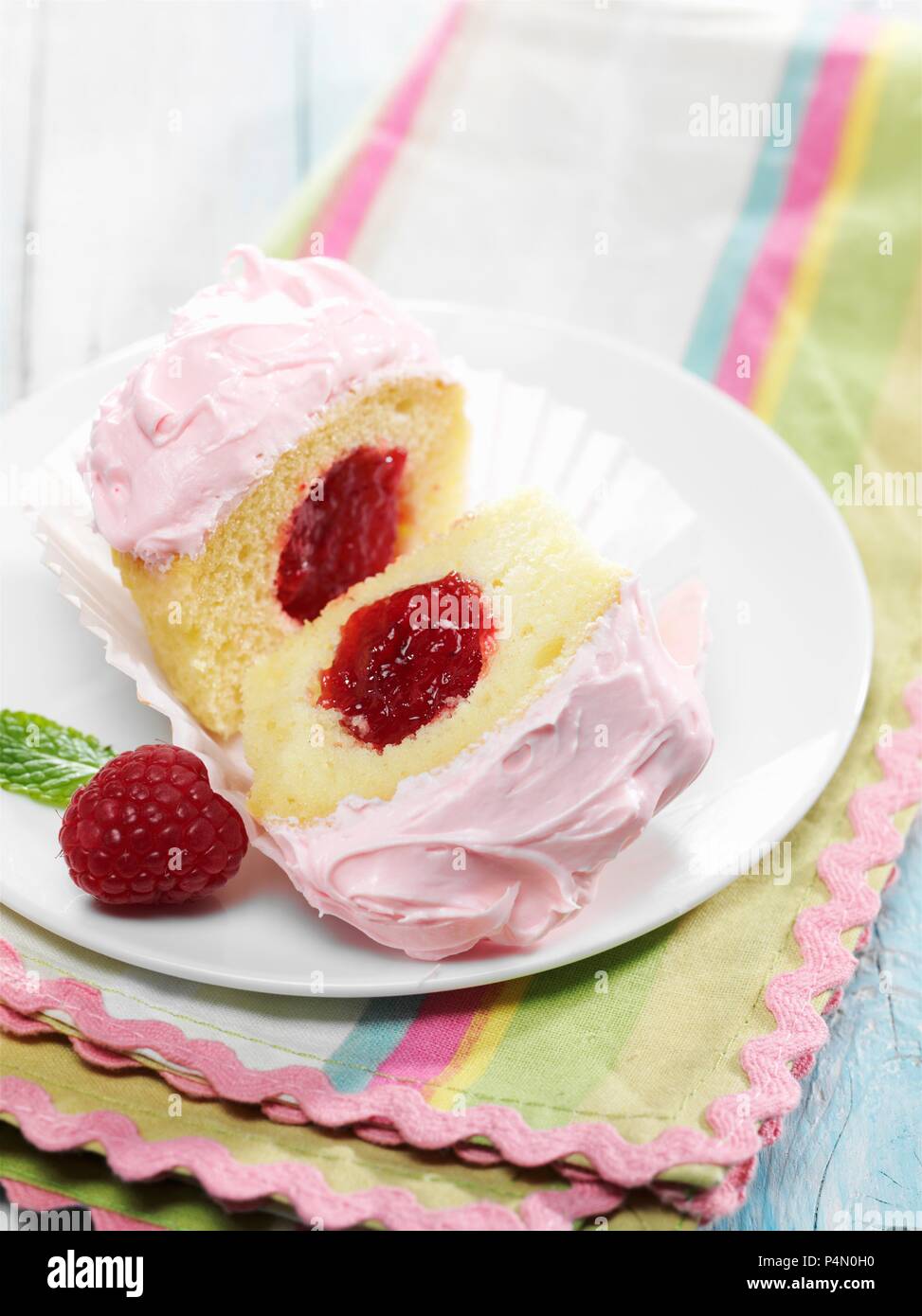 Cupcake à la vanille Confiture de framboises avec du glaçage rose et centre Banque D'Images