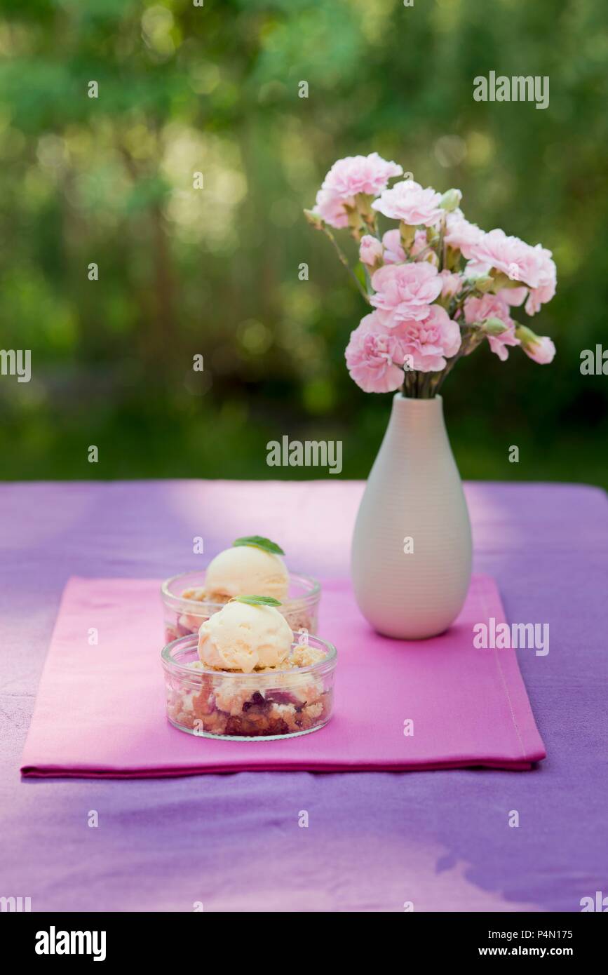 Crumble aux fraises avec glace à la vanille en dessert plats sur une table de jardin Banque D'Images