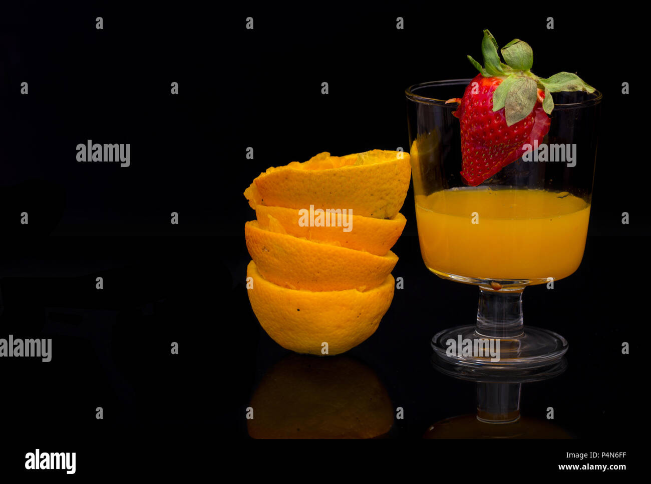 Libre d'oranges avec verre de jus et de fraise sur le bord sur un fond noir Banque D'Images