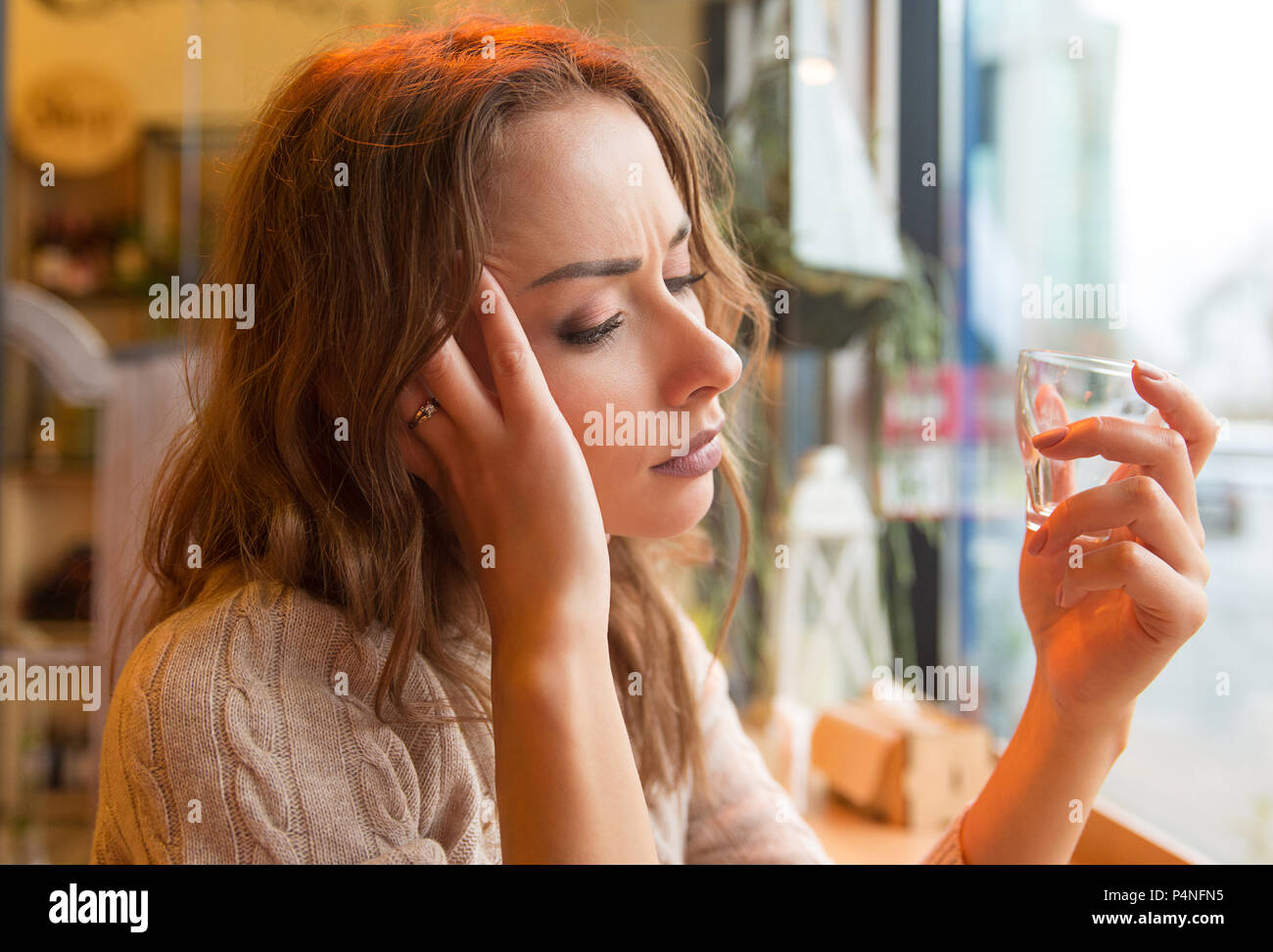 Vue latérale du jeune femme solitaire souffrant d'alcoolisme et de boire seul en bar à la recherche appuyée Banque D'Images