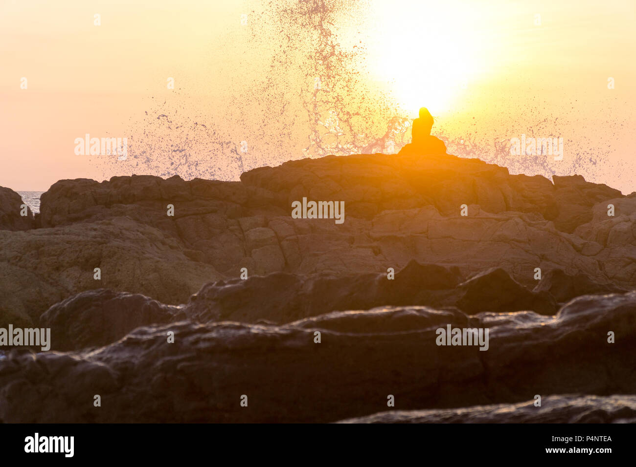 Les femmes assises sur des rochers à la plage avec de grosses vagues. Banque D'Images