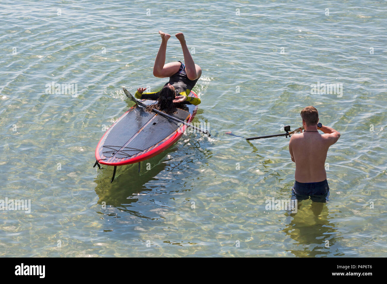 Bournemouth, Dorset, UK. 23 juin 2018. Météo France : belle matinée ensoleillée à chaud des plages de Bournemouth en tant que visiteurs, chef de la station tôt pour obtenir un espace avant qu'il soit emballé plus tard et à profiter du soleil à la hausse des températures pour la canicule. Les amis s'amusant rester au frais sur leurs paddleboards dans la mer. La capture de l'instant ! Femme en paddleboard paddle board. Credit : Carolyn Jenkins/Alamy Live News Banque D'Images