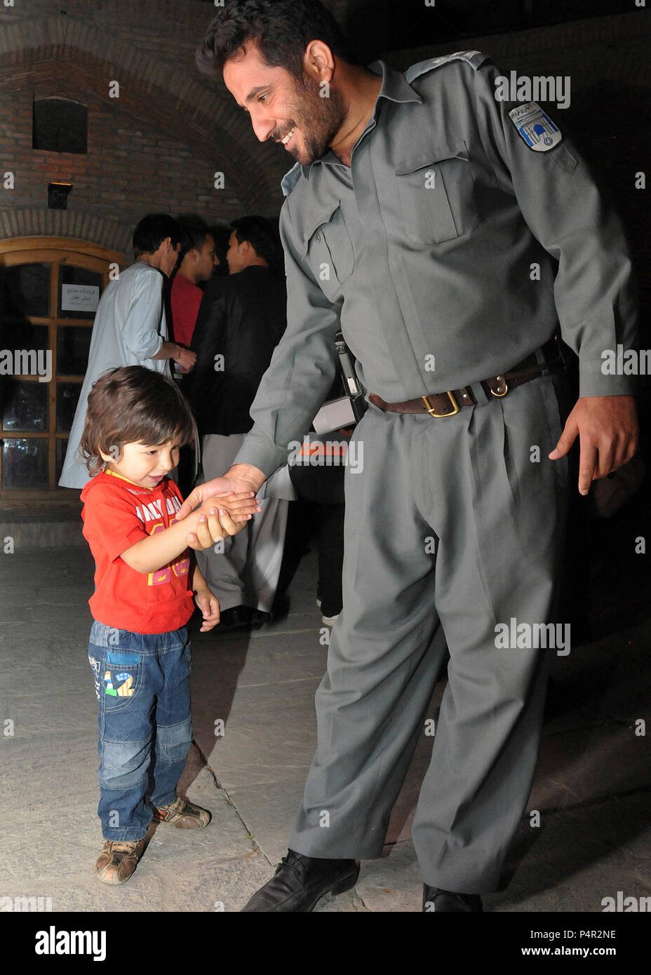 Kaboul -- (21 mai 2012), un agent de la Police nationale afghane frappe la main d'un enfant afghan au cours du 1er Festival du film Police tenue à l'Babur Gardens, 21 mai. La semaine du festival a été conçu pour ouvrir un dialogue culturel entre l'ANP et de la communauté afghane qui aideront à améliorer la communication et l'aide à l'élaboration de nouveaux, des perceptions positives de la police afghane. La Marine américaine Banque D'Images