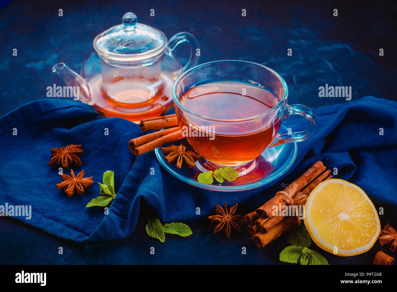 Tasse en verre de thé noir, , nappes, rondelles de citron, la cannelle, l'anis étoile et de feuilles de menthe sur un fond sombre. En-tête de la photographie alimentaire sombre avec l'exemplaire Banque D'Images