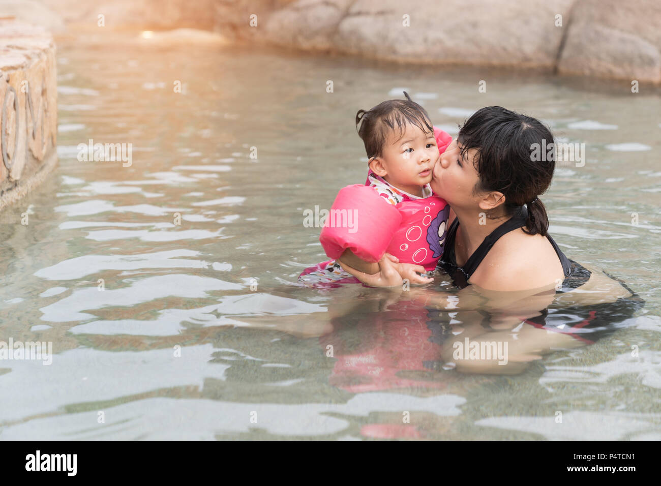 Mère et bébé fille asiatique baiser sur le parc de l'eau, maison de vacances d'arrière-plan des concepts de la mer. Banque D'Images