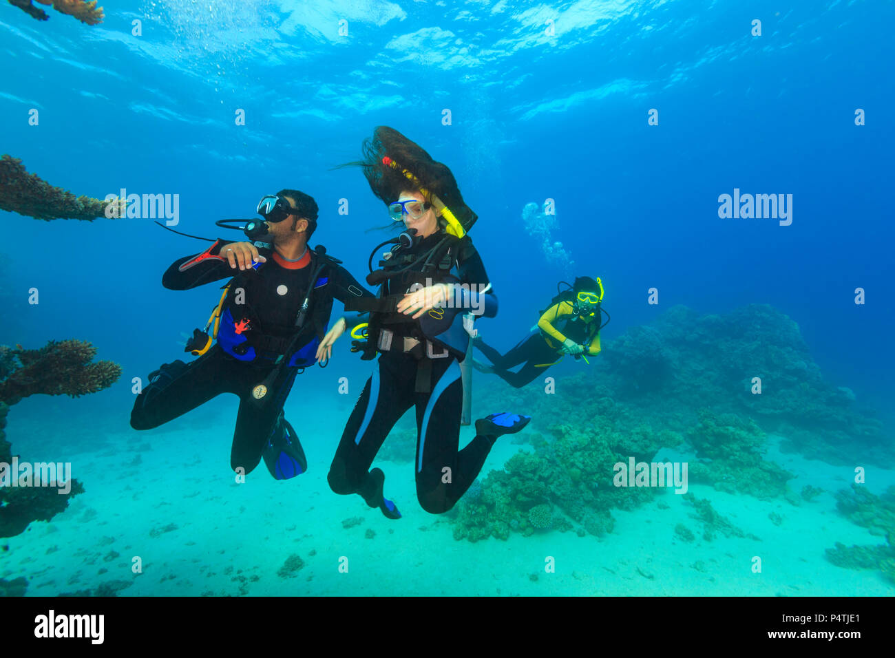 Explorer les gens sous l'eau . Deux personnes adultes en plongée première fois le récif tropical avec fond bleu, beaux récifs et de petits poissons. Man pointing Banque D'Images