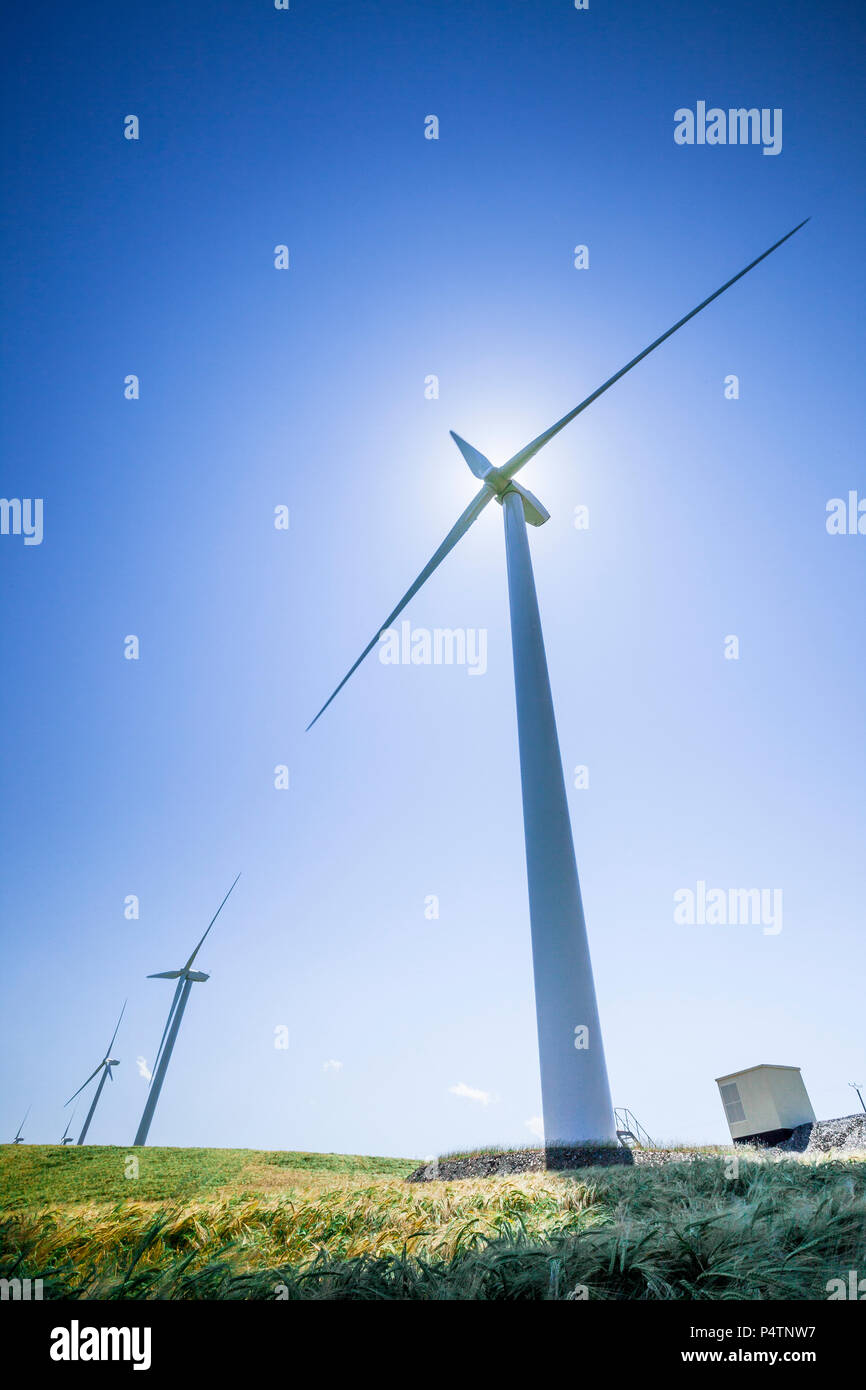 Une série de trois éoliennes dans un moulin à vent park contre un ciel bleu clair. Banque D'Images