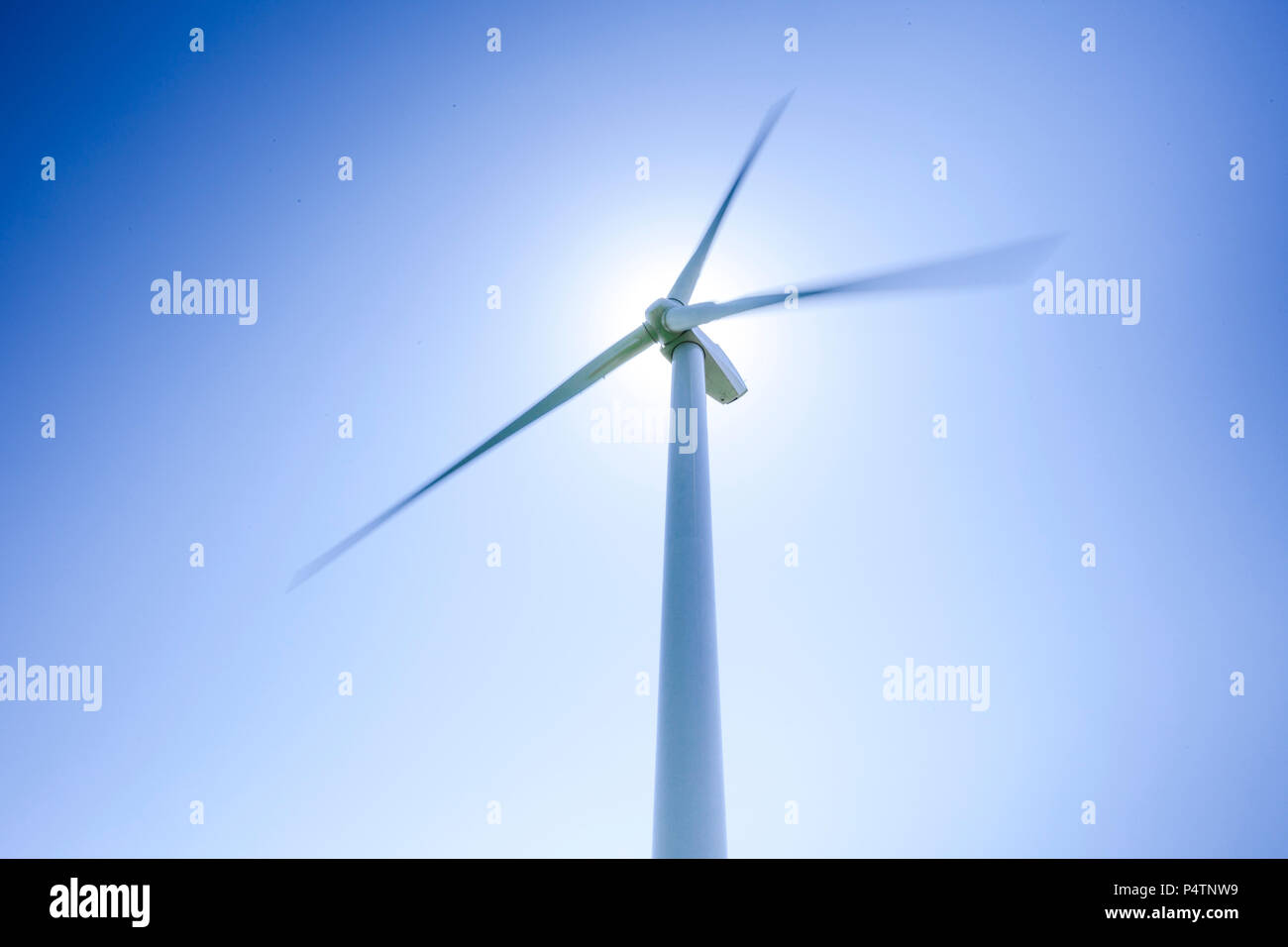Wind turbine in action dans un moulin park contre un ciel bleu clair. Banque D'Images