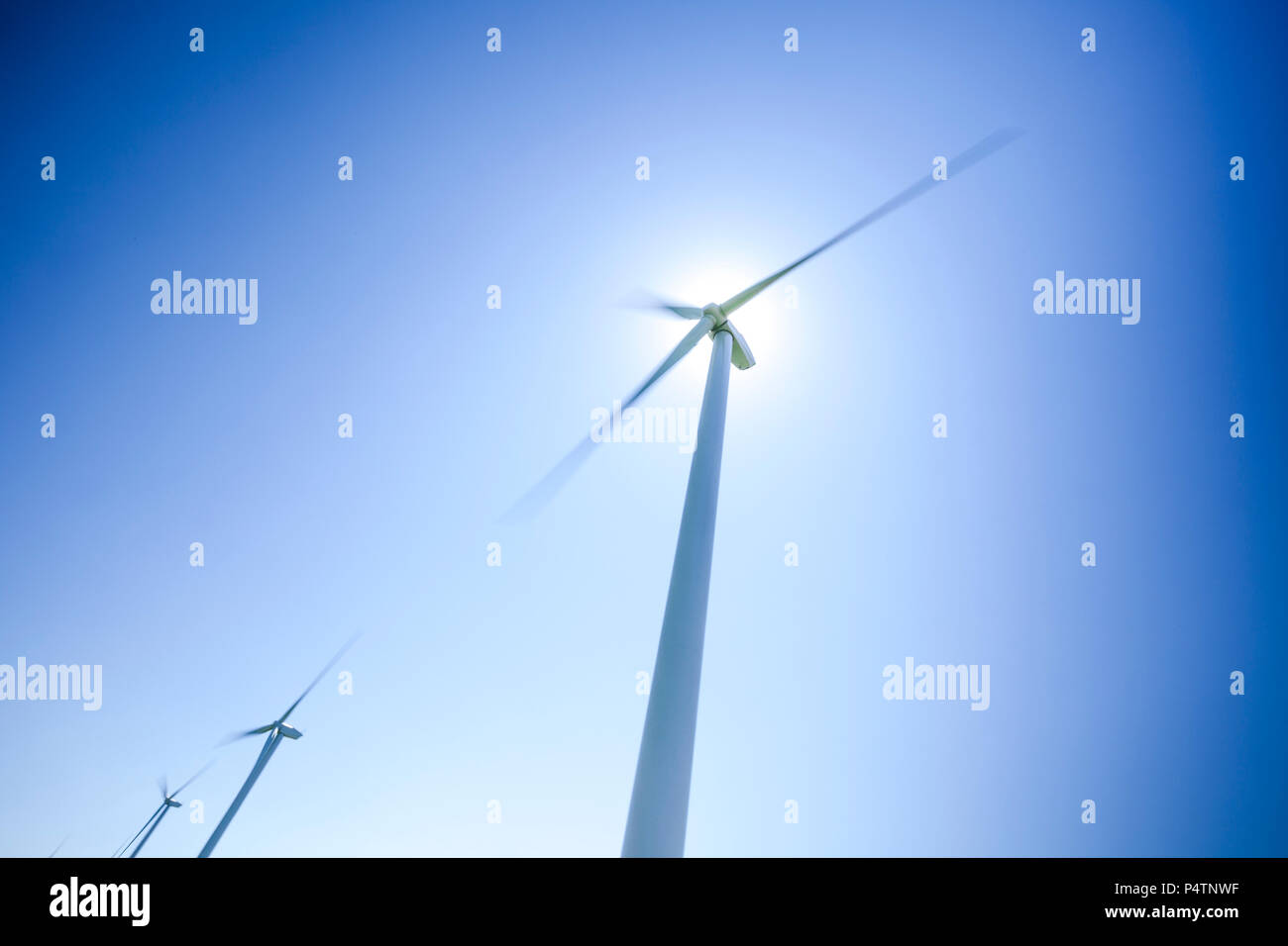 Une série de trois éoliennes dans un moulin à vent park contre un ciel bleu clair. Banque D'Images