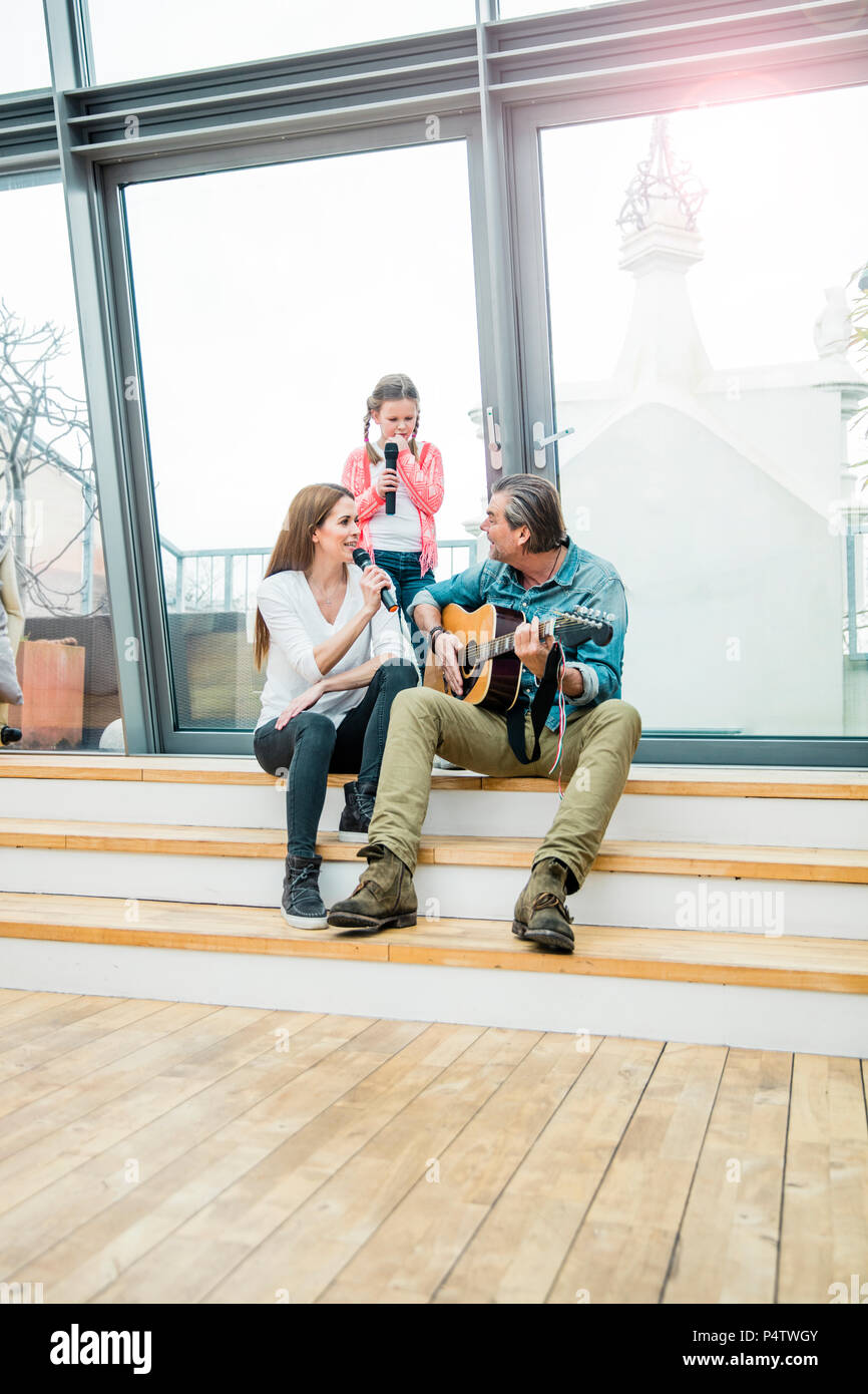 Famille heureuse dans les escaliers à l'extérieur de faire de la musique ensemble Banque D'Images