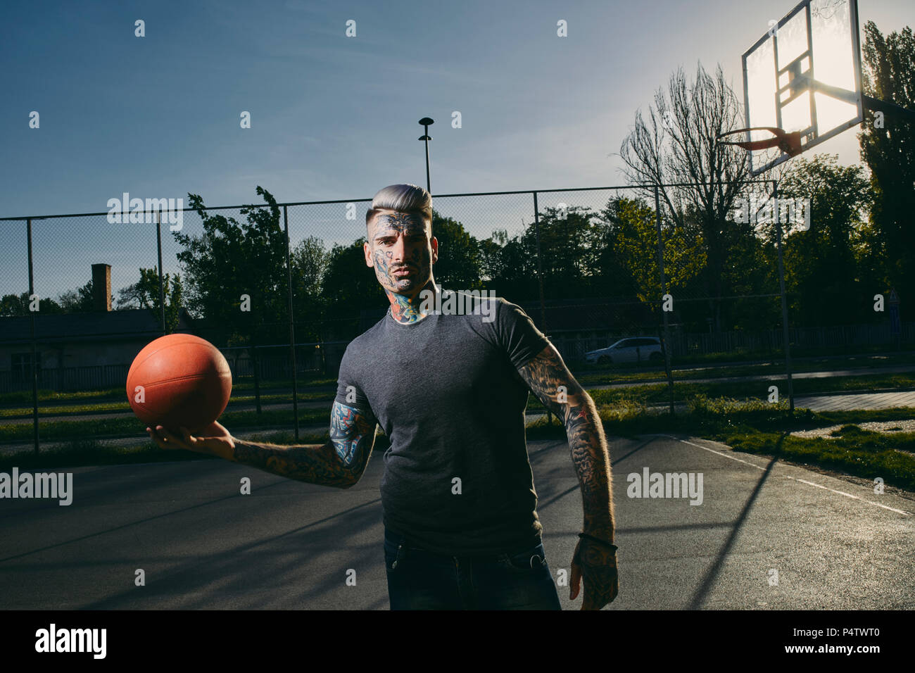 Portrait de jeune homme tatoué avec le basket-ball sur cour Banque D'Images