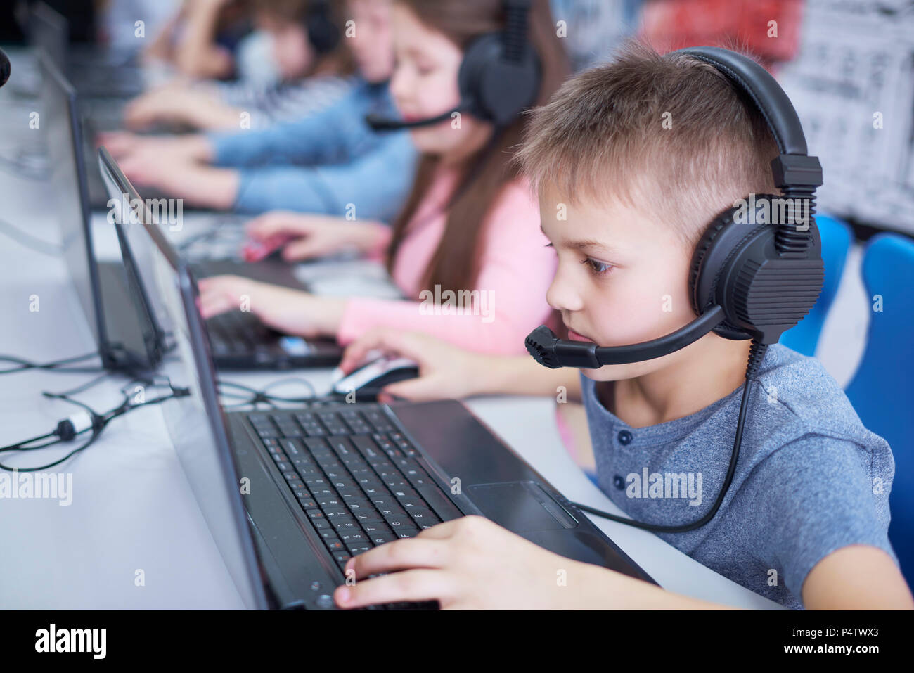 Les élèves portant des casques et à l'aide d'ordinateurs portables à l'école Banque D'Images