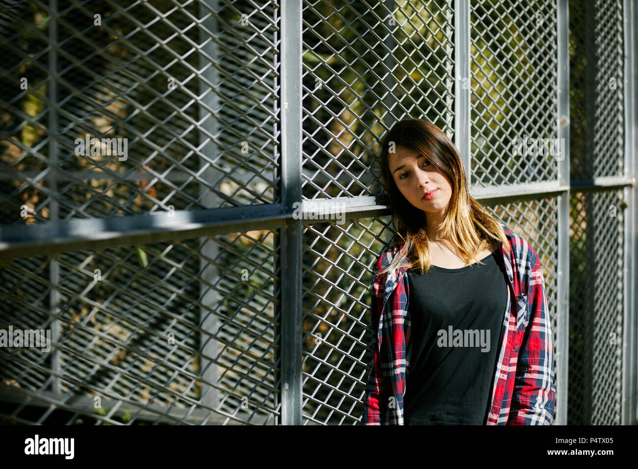 Portrait de belle jeune femme appuyée contre une clôture Banque D'Images