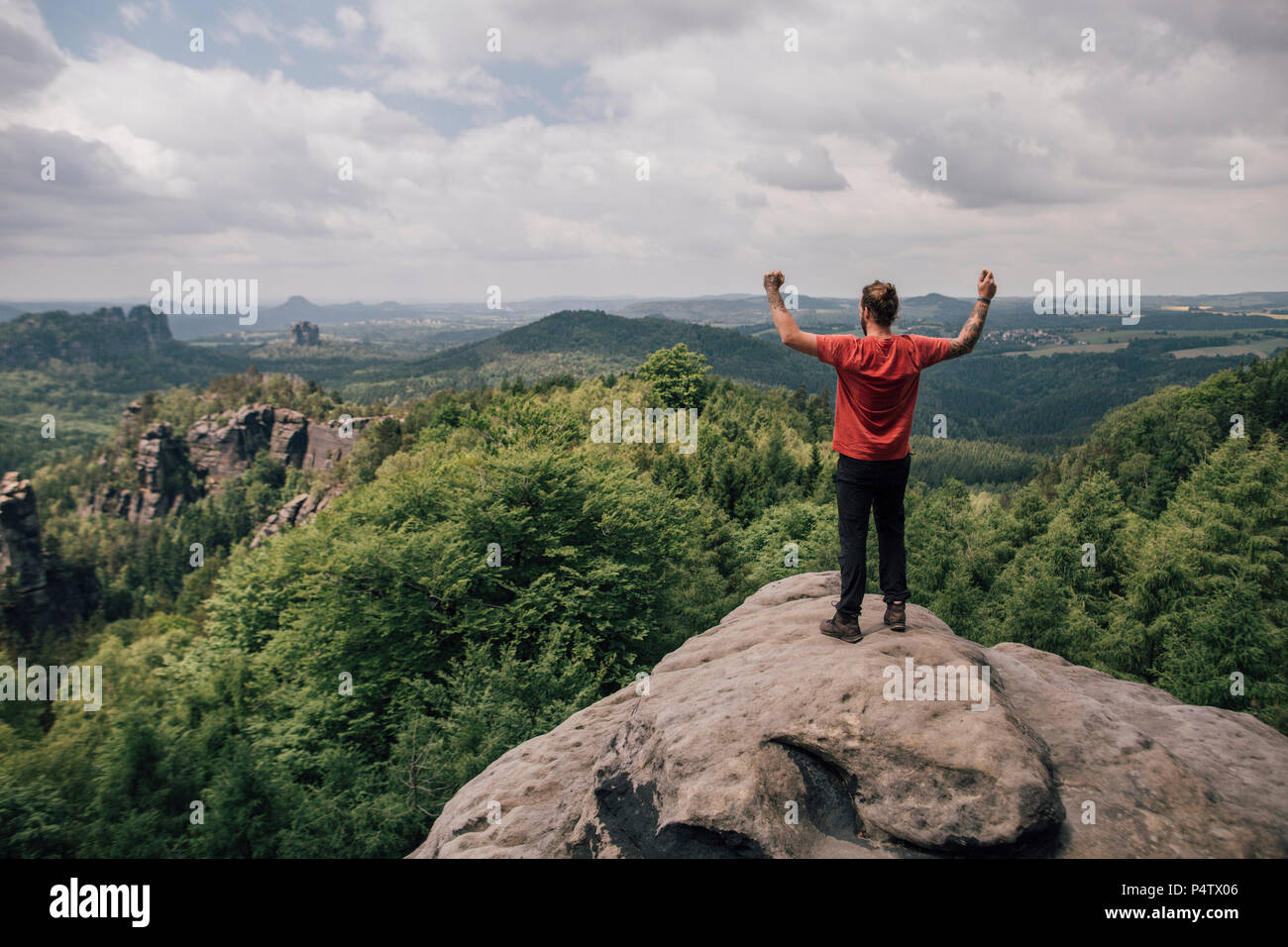 Allemagne, Saxe, des montagnes de grès de l'Elbe, l'homme en randonnée debout sur rock cheering Banque D'Images